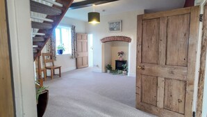 A room with a wooden door, a fireplace, a staircase, and a hanging light fixture. - The Manor House at Kenwick Lodge (Ellesmere)