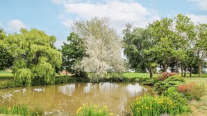 A serene park with a pond, lush greenery, and trees. - The Manor House at Kenwick Lodge (Ellesmere)