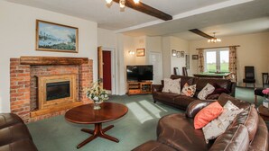 A living room with a brick fireplace, a television, a pool table, and a sofa. - The Manor House at Kenwick Lodge (Ellesmere)