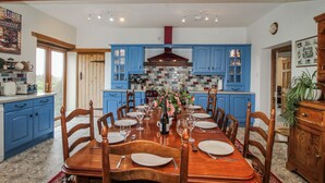 A dining room with a wooden table set for six, blue cabinets, and a tiled backsplash. - The Manor House at Kenwick Lodge (Ellesmere)