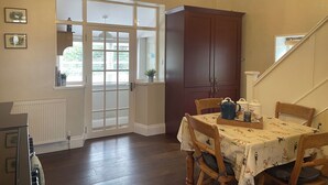 A dining area with a table set for four, wooden chairs, a cabinet, and a radiator. - Warren House Cottage (Market Rasen)