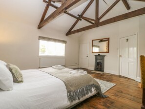 Une chambre à coucher avec un grand lit, une cheminée, une fenêtre avec des stores et une porte.