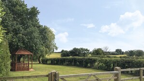 A wooden gate leading to a park with a gazebo and neatly trimmed hedges. - Warren House Cottage (Market Rasen)