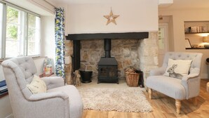 A cozy living room with a stone fireplace, two grey armchairs, a fluffy rug, and a star decoration on the wall. - Market House (Weymouth)