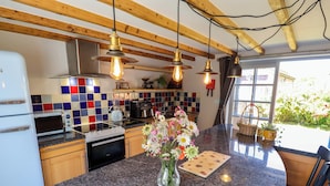A kitchen with a granite countertop, a white refrigerator, a microwave, a stove, and hanging pendant lights. - Gables Cottage (Market Rasen)