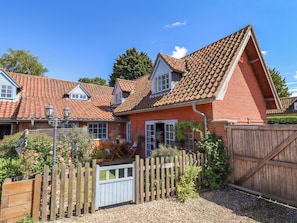 A house with a red brick exterior, a tiled roof, and a wooden fence.