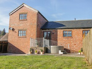 A two-story brick house with a front porch, a small staircase, and a fenced yard. - Old Hall Barn 2 (Church Stretton)