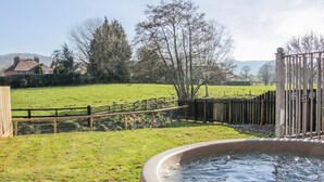 Una vasca idromassaggio in un giardino privato con recinzione in legno e prato.