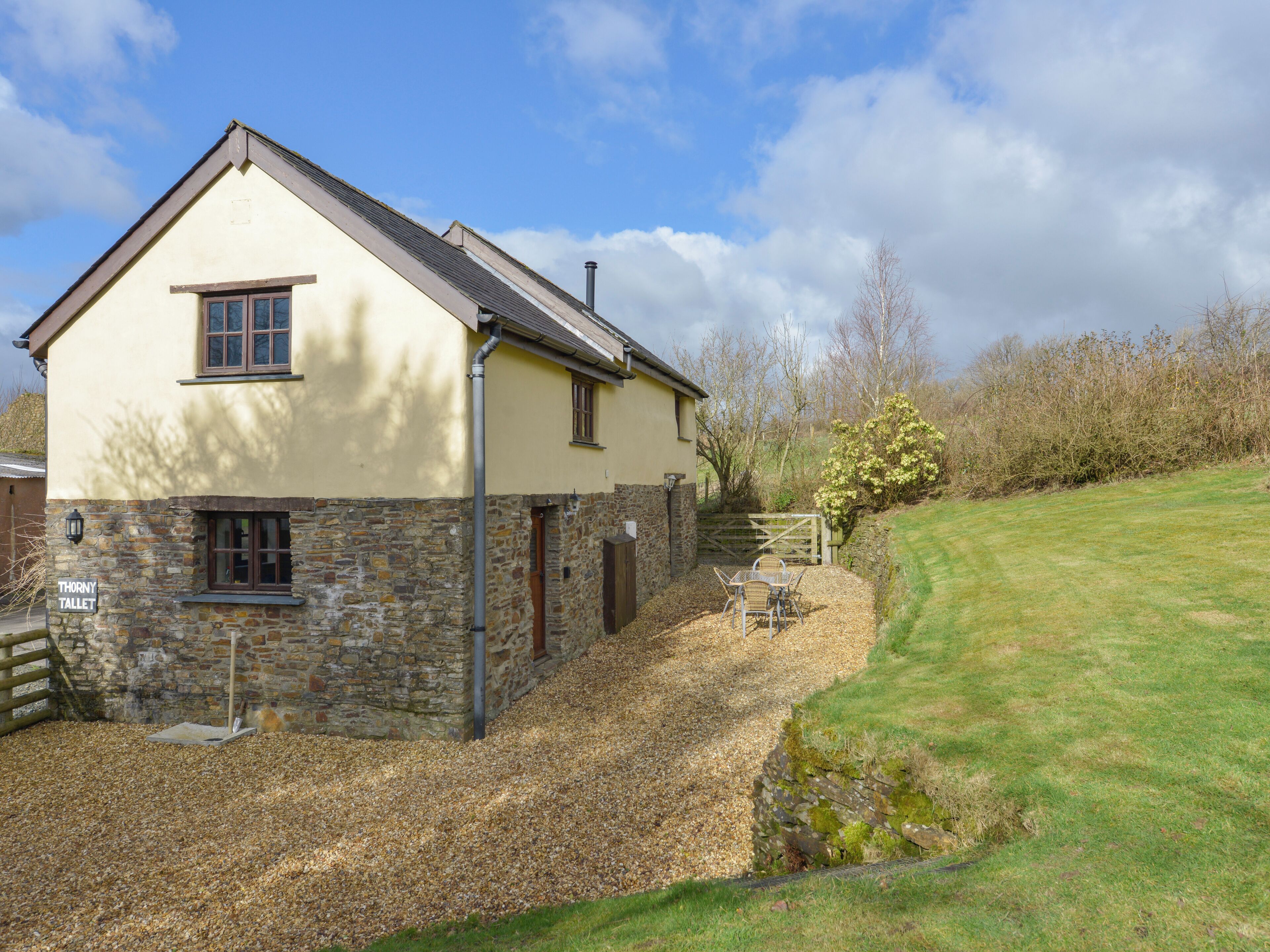A two-story house with a stone foundation and a sloped roof.