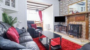 A modern living room with a leather sofa, red carpet, and a stone wall fireplace.