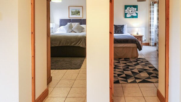 Un pasillo que conduce a un dormitorio con una cama, una mesita de noche y una lámpara.