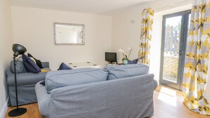 A modern living room with a grey sofa, a floor lamp, and a flat-screen TV. - Puddleducks (Sherborne)