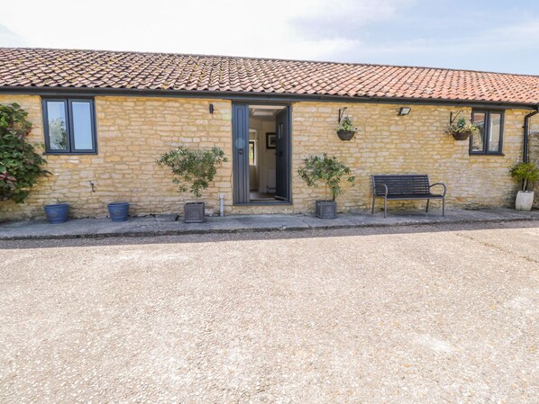 A stone building with a tiled roof, a bench, and potted plants. - Puddleducks (Sherborne)