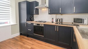 Uma cozinha moderna com armários escuros, fogão a gás, micro-ondas e torradeira.