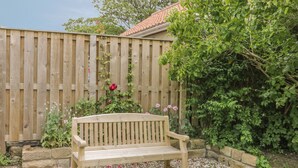 A wooden bench in a garden with a wooden fence and greenery. - Stakesby House Apartment 3 (Whitby)