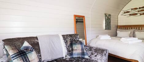 A cozy room with a sofa, a bed, a mirror, and a wall art piece.