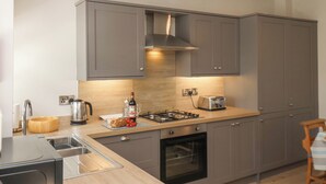 Eine moderne Küche mit grauen Schränken, einem Gasherd, einem Toaster und einer Spüle.