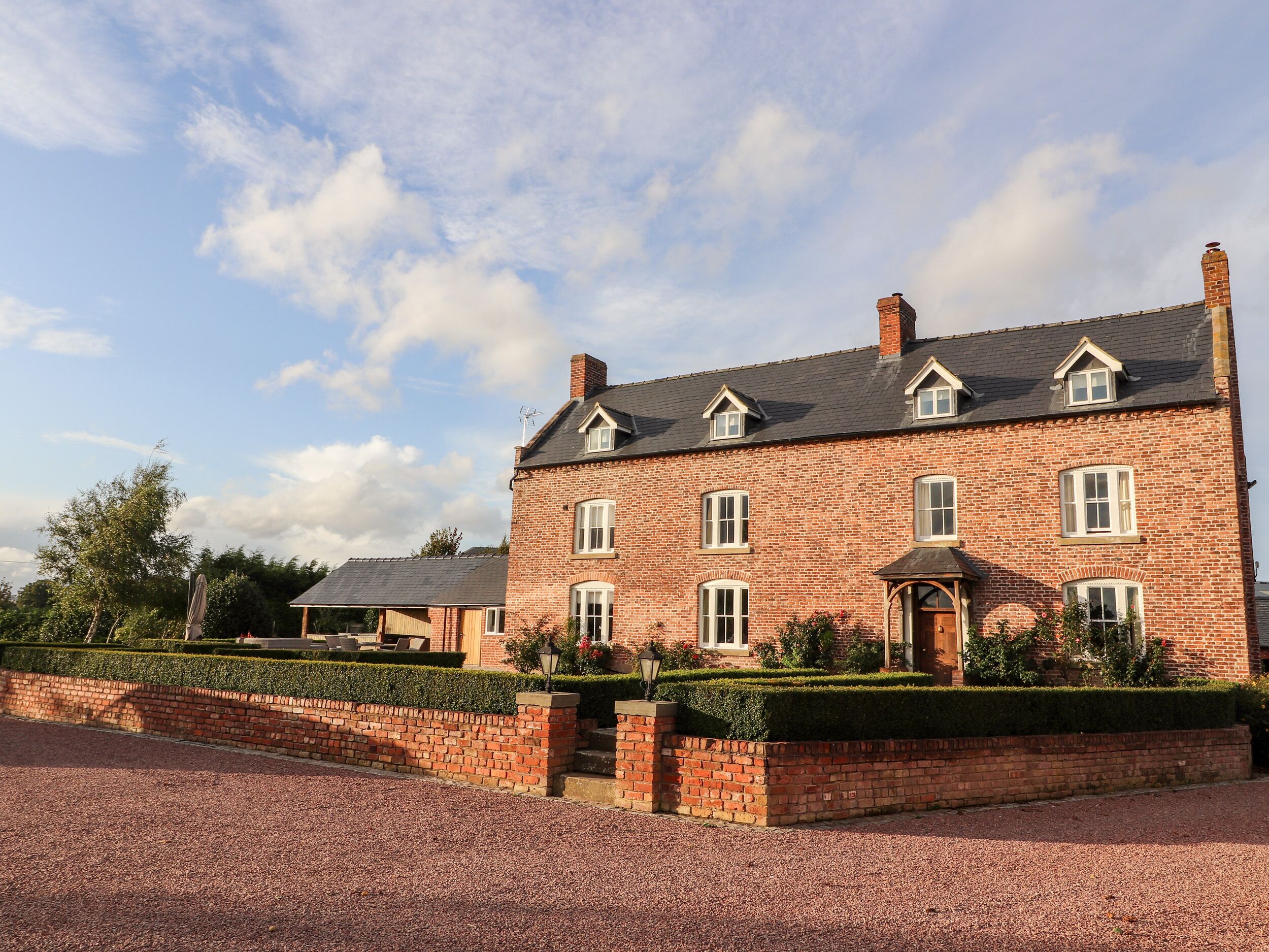 A large brick building with multiple windows and a well-maintained garden.