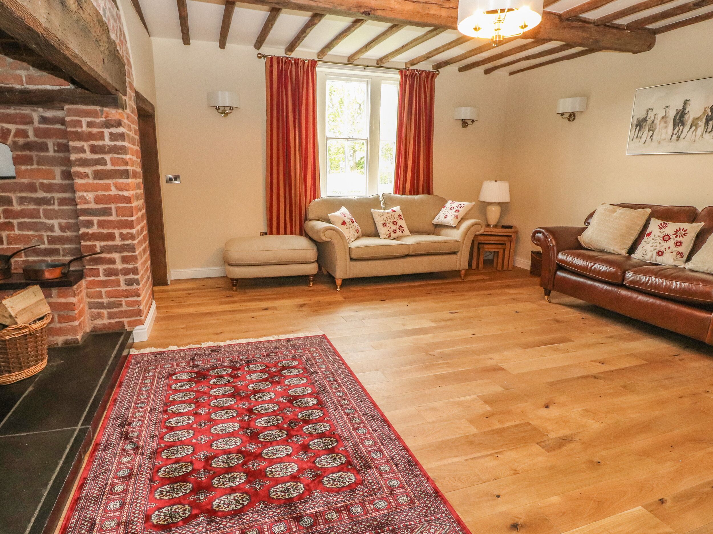 A cozy living room with a fireplace, two sofas, a rug, and a wooden floor.