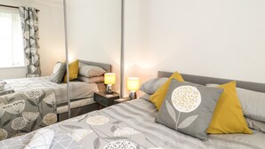 A hotel room with a large bed, a bedside table with lamps, a mirror, and a window with curtains.