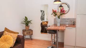 A compact living space with a kitchenette, a dining area, and a seating area with a brown sofa and cushions.
