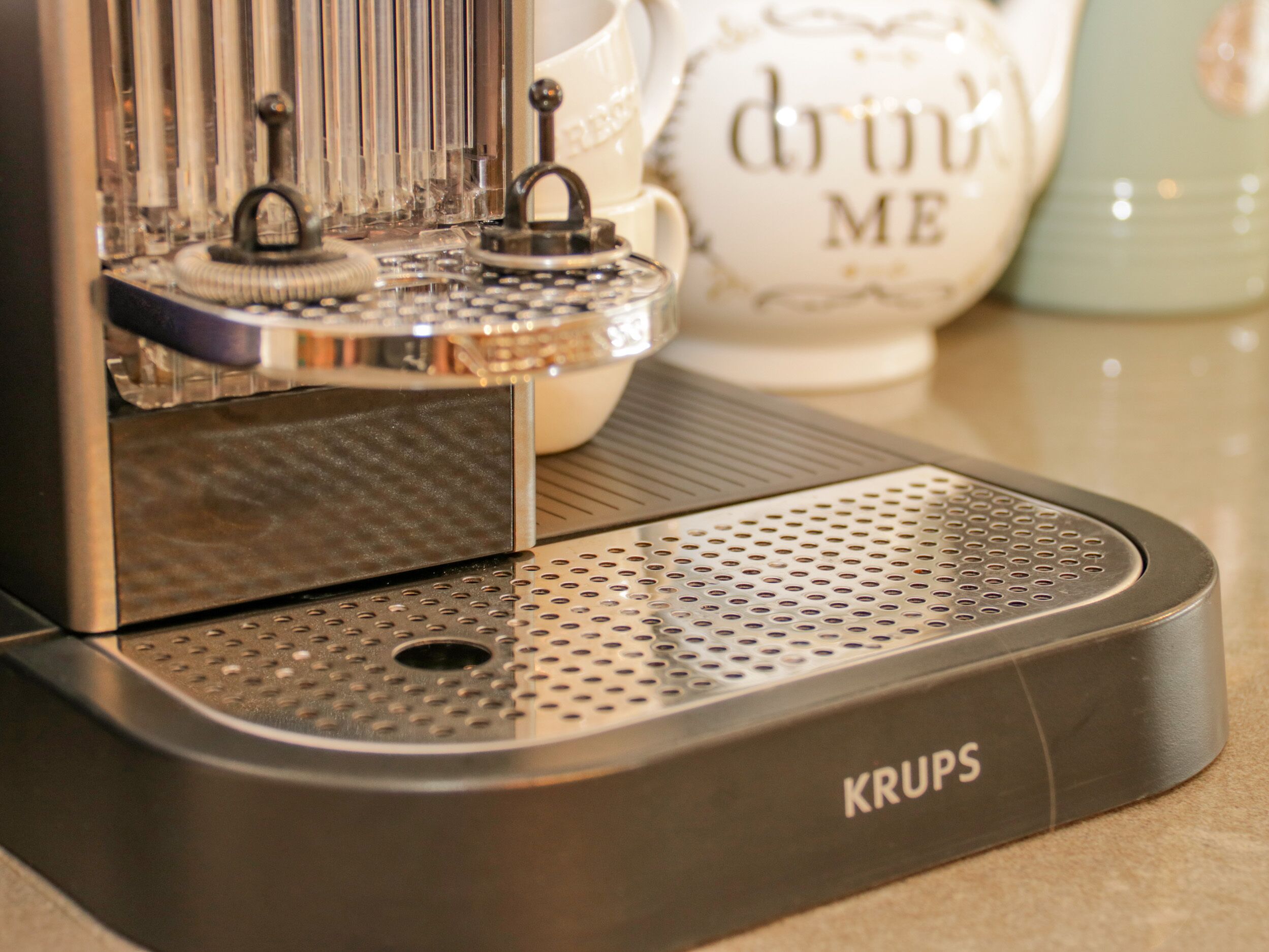A Krups coffee machine with a perforated drip tray and a control panel.