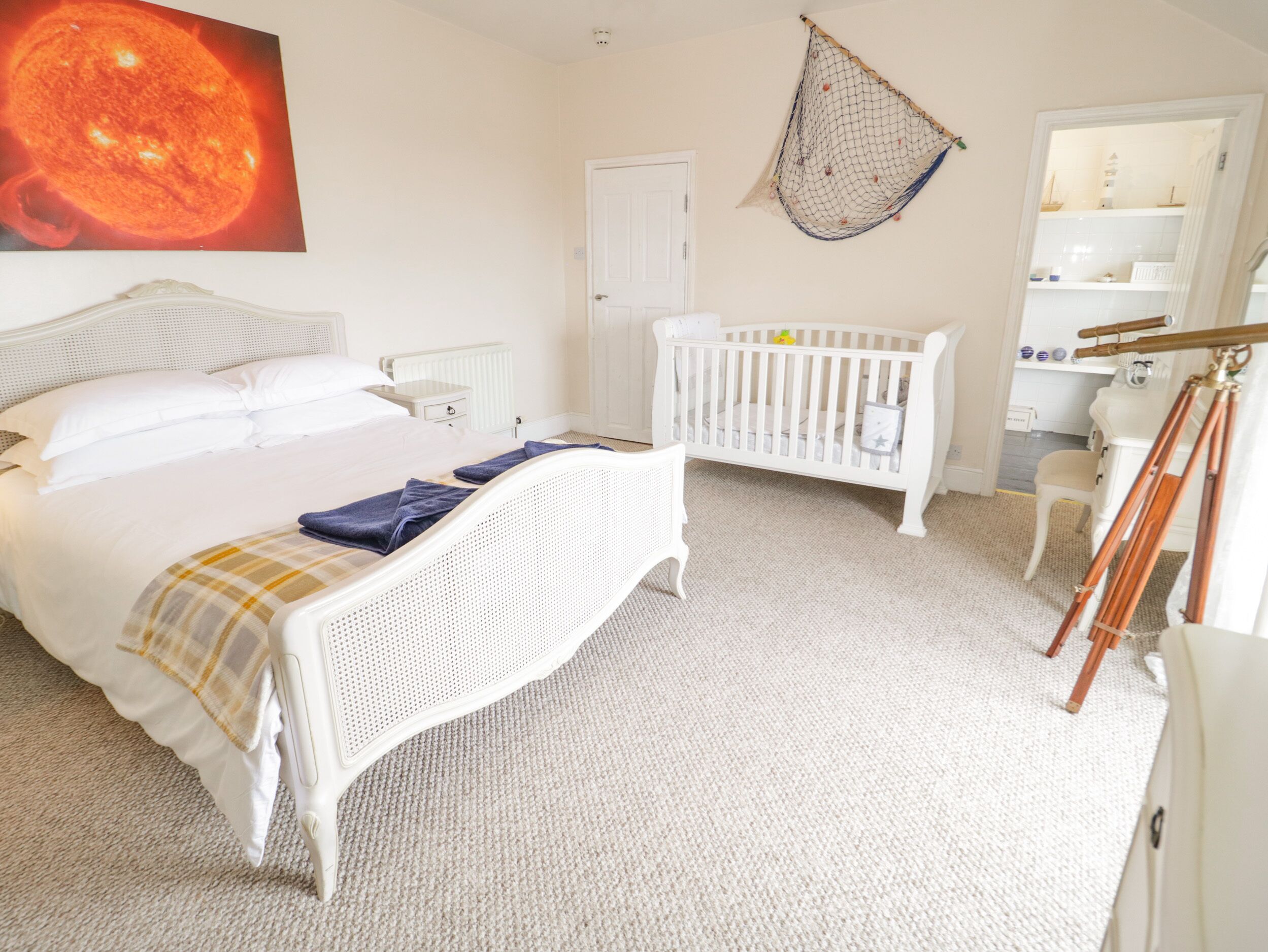 Un dormitorio con cama, cuna, hamaca y telescopio.