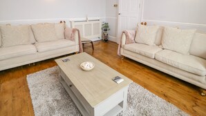 Una sala de estar con dos sofás color beige, una mesa de centro de madera y un tapete blanco.