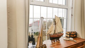 Un escritorio de madera con un telescopio, un velero modelo y un cofre del tesoro.