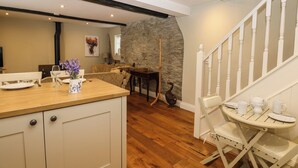 Un intérieur chaleureux avec une table à manger en bois, un mur en pierre et un escalier.