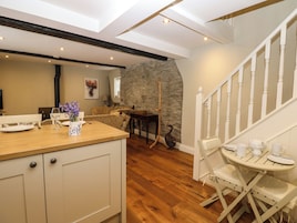 Un interior acogedor con una mesa de comedor de madera, una pared de piedra y una escalera.