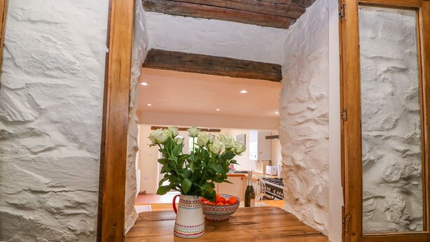 Ein rustikales Interieur mit einem Holztisch, einer Blumenvase und einer Tomatenschale.