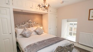 A bedroom with a large bed, ornate headboard, and a chandelier. - Castle Keep at Stanhope Castle (Bishop Auckland)