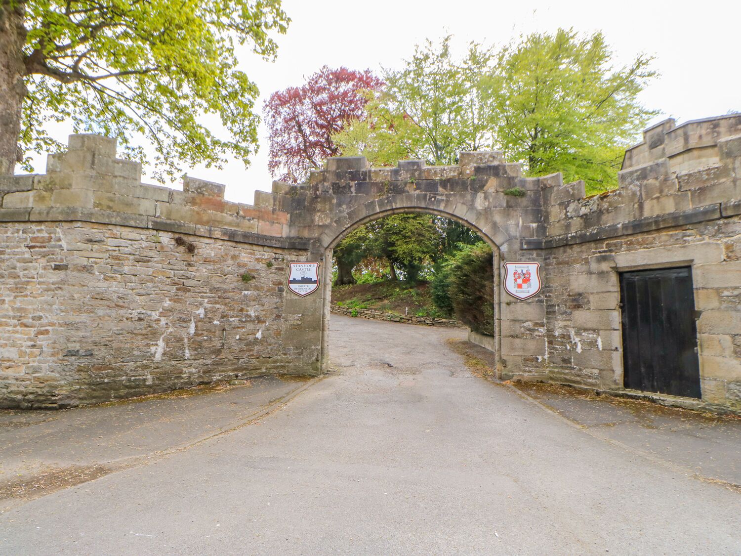 Un arco de piedra que da paso a un patio con un letrero que indica que forma parte del Castillo Stanhope.