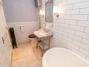 A bathroom with white tiled walls, a white sink, a mirror, a toilet, and a bathtub. - Castle Keep at Stanhope Castle (Bishop Auckland)