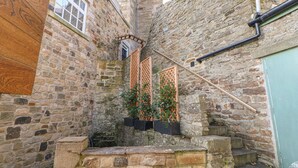 A narrow stone staircase leading to a wooden door, with a window and a wooden panel on the left. - Castle Keep at Stanhope Castle (Bishop Auckland)