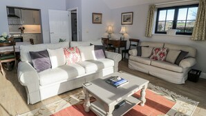 A living room with two sofas, a coffee table, and a dining area with a table and chairs.