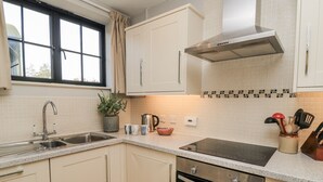 A modern kitchen with a double sink, stainless steel appliances, and a window with curtains.