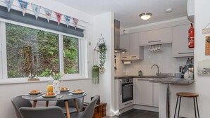 A modern kitchen with white cabinets, a built-in oven, and a small island with a sink. - 3 Dolphin Court (Brixham)