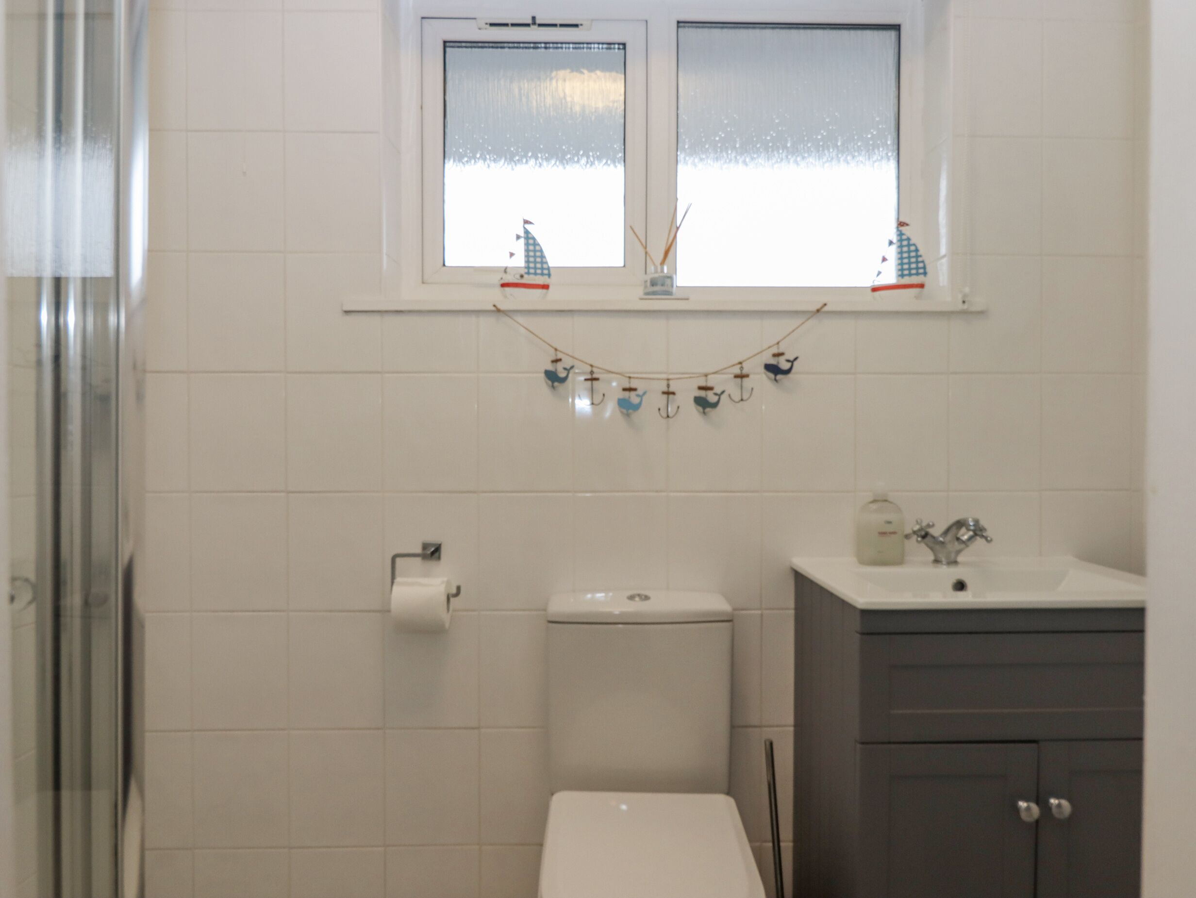 A bathroom with a toilet, sink, and window.