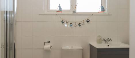 A bathroom with a toilet, sink, and window.