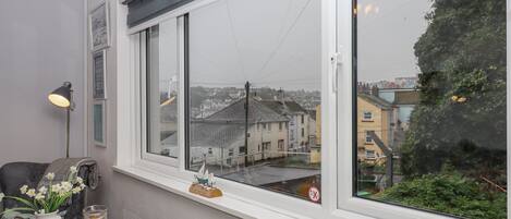 A room with a large window overlooking a residential area, a table with breakfast items, and a decorative sailboat on the windowsill.