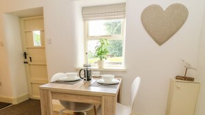 A dining area with a table set for two, a coffee maker, and a heart-shaped decoration on the wall. - Spens Farm Cottage (Lancaster)