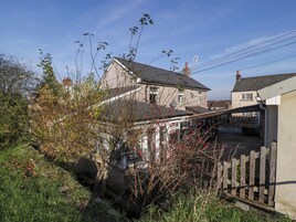 A residential area with houses, a wooden fence, and a garden with various plants and shrubs.