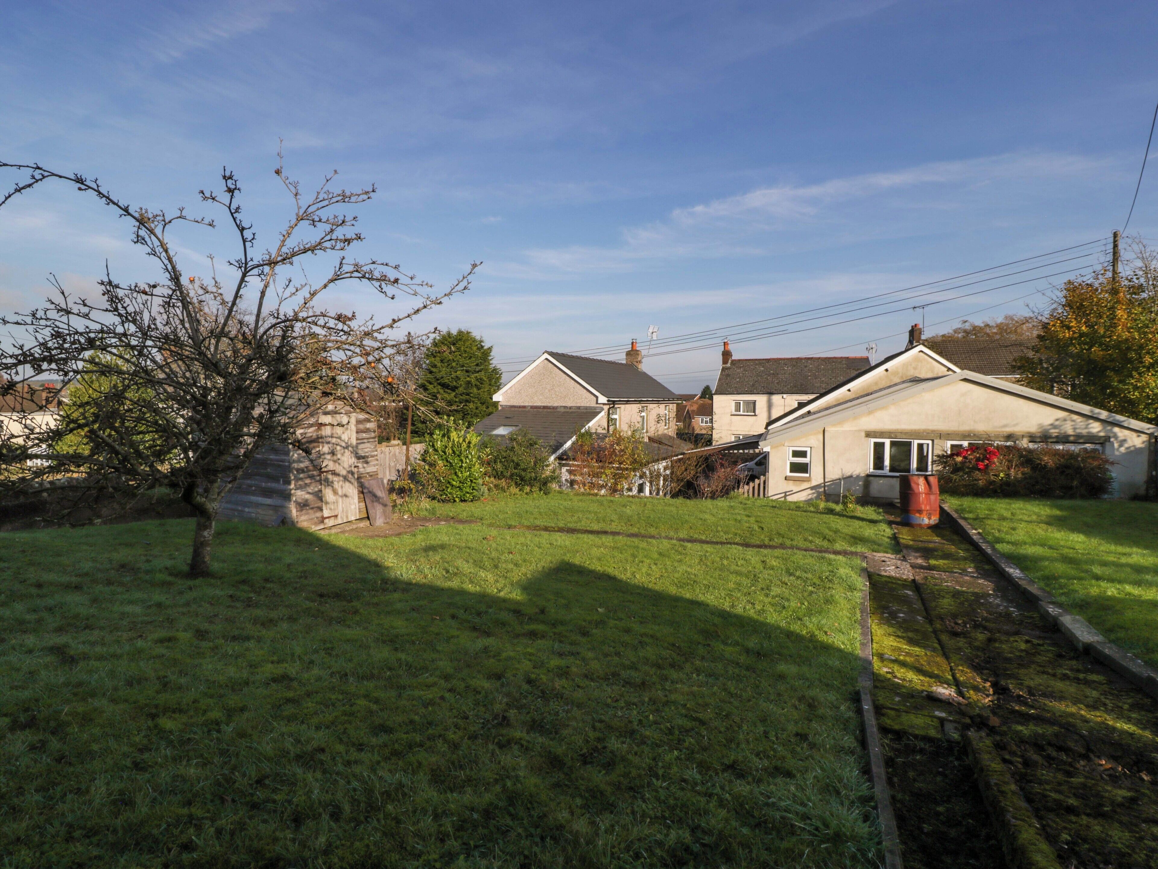 A residential area with houses, a tree, and a railway track.