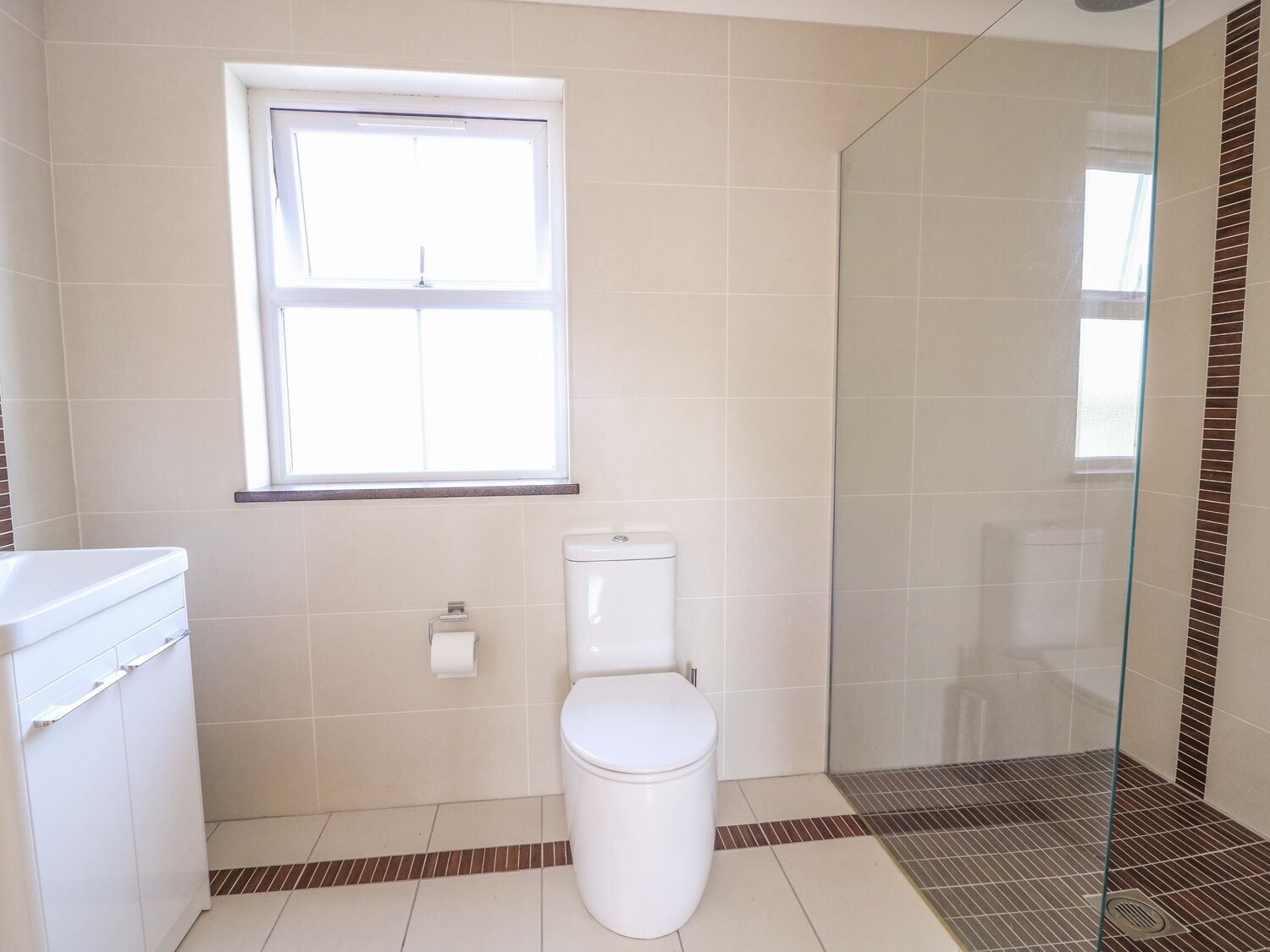 Un baño con inodoro, ventana y cabina de ducha de vidrio.
