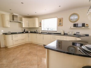 A modern kitchen with a curved island, a built-in stove, and a window providing natural light.