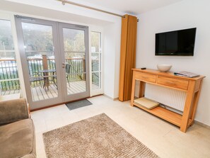 Relax in a comfortable living space with a sofa, TV, and sliding door leading to an outdoor deck.