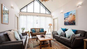 Un salón amplio con dos sofás de cuero, una mesa de centro de madera y un gran ventanal con cortinas.