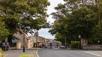 A street lined with stone buildings, a motorbike parked on the side, and a bus stop.